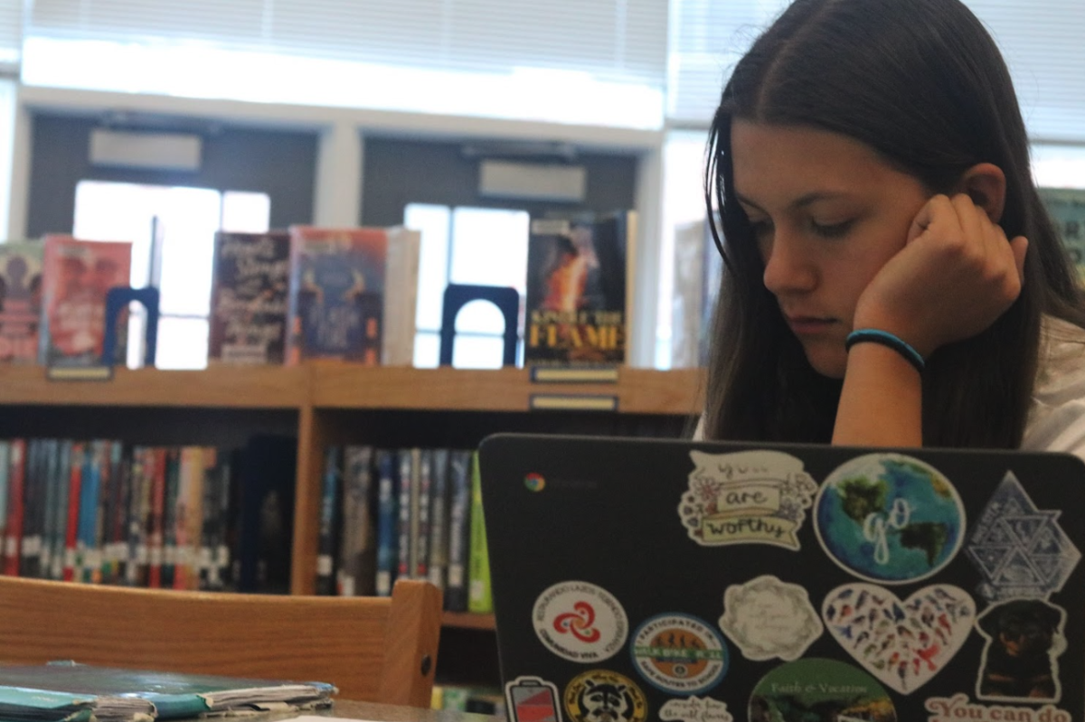 Student works on assignments at a table in the library.